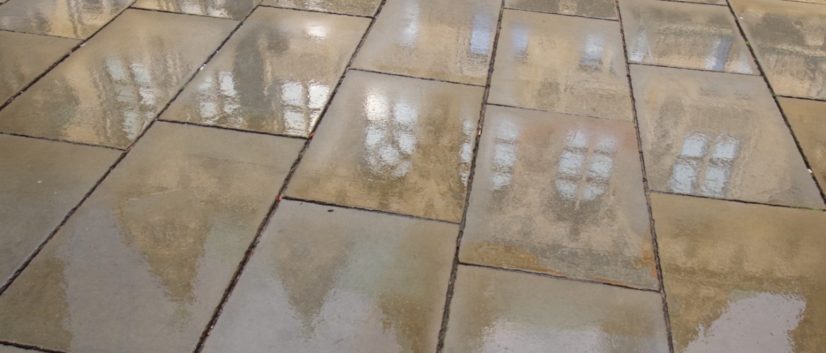 Nach dem Regen spiegelt sich die Fassade in den Steinplatten